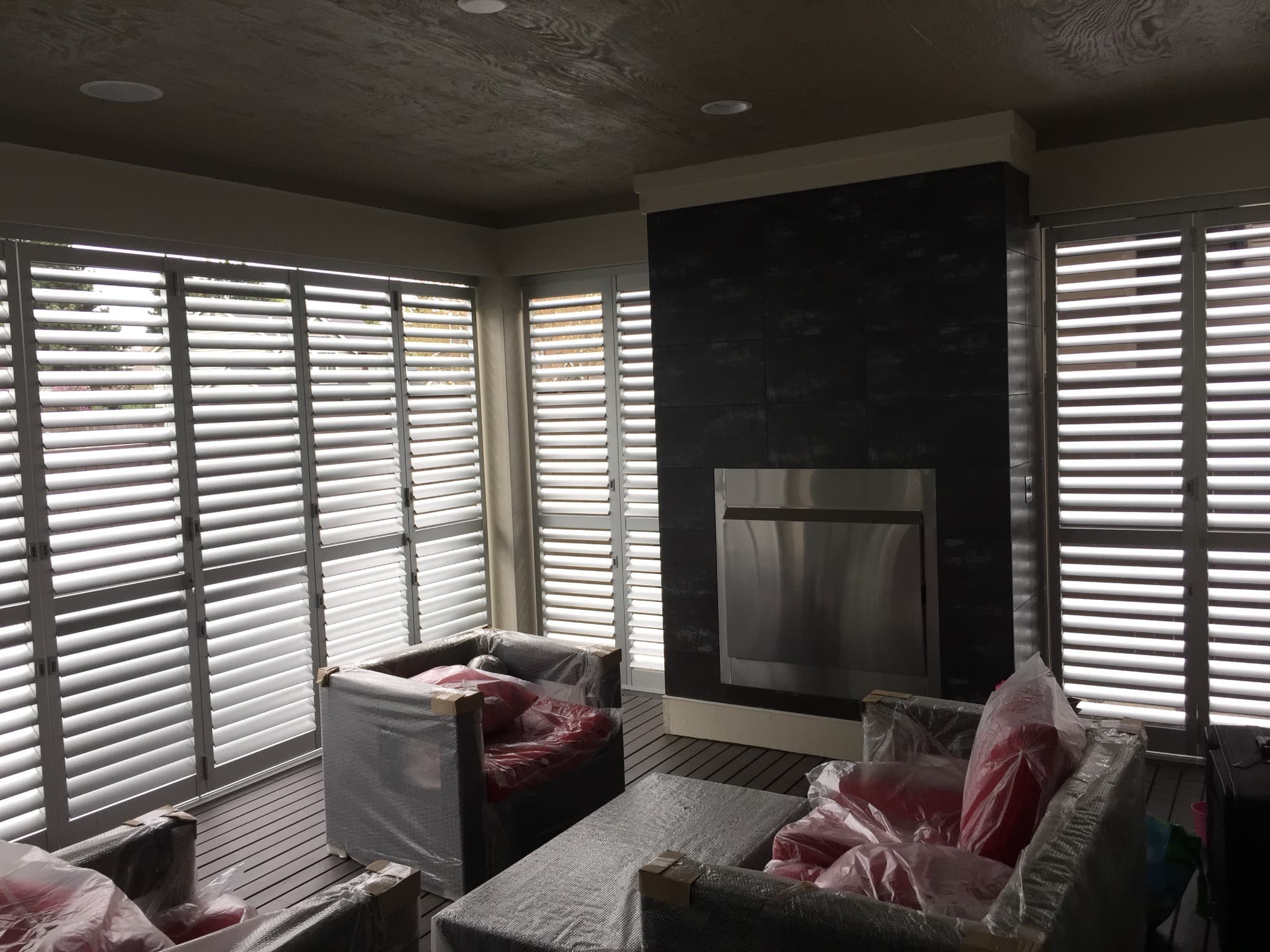 Louvered shutters surrounding an outdoor seating area with a fireplace