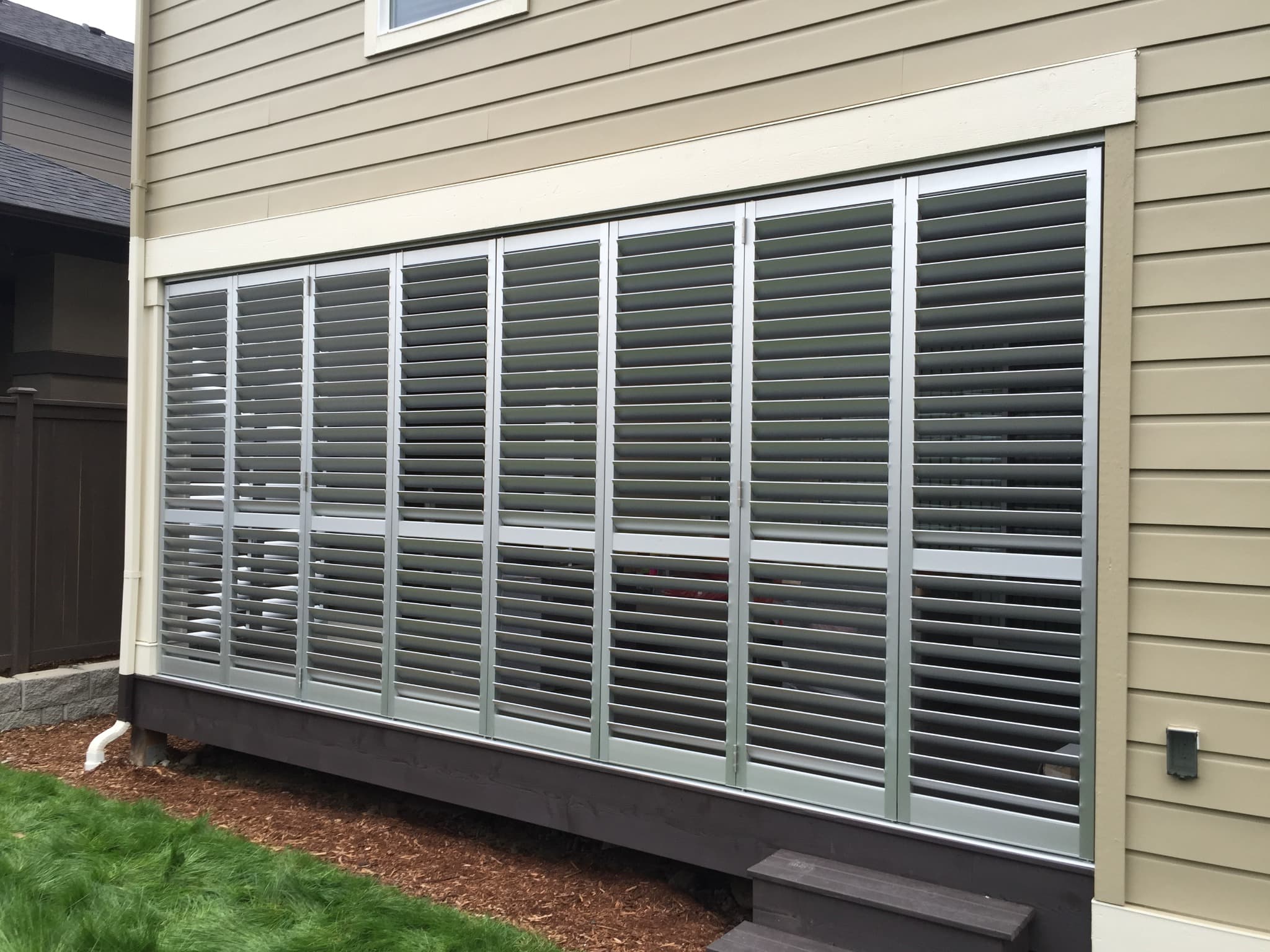 Exterior view of a screened patio fitted with aluminum shutter panels