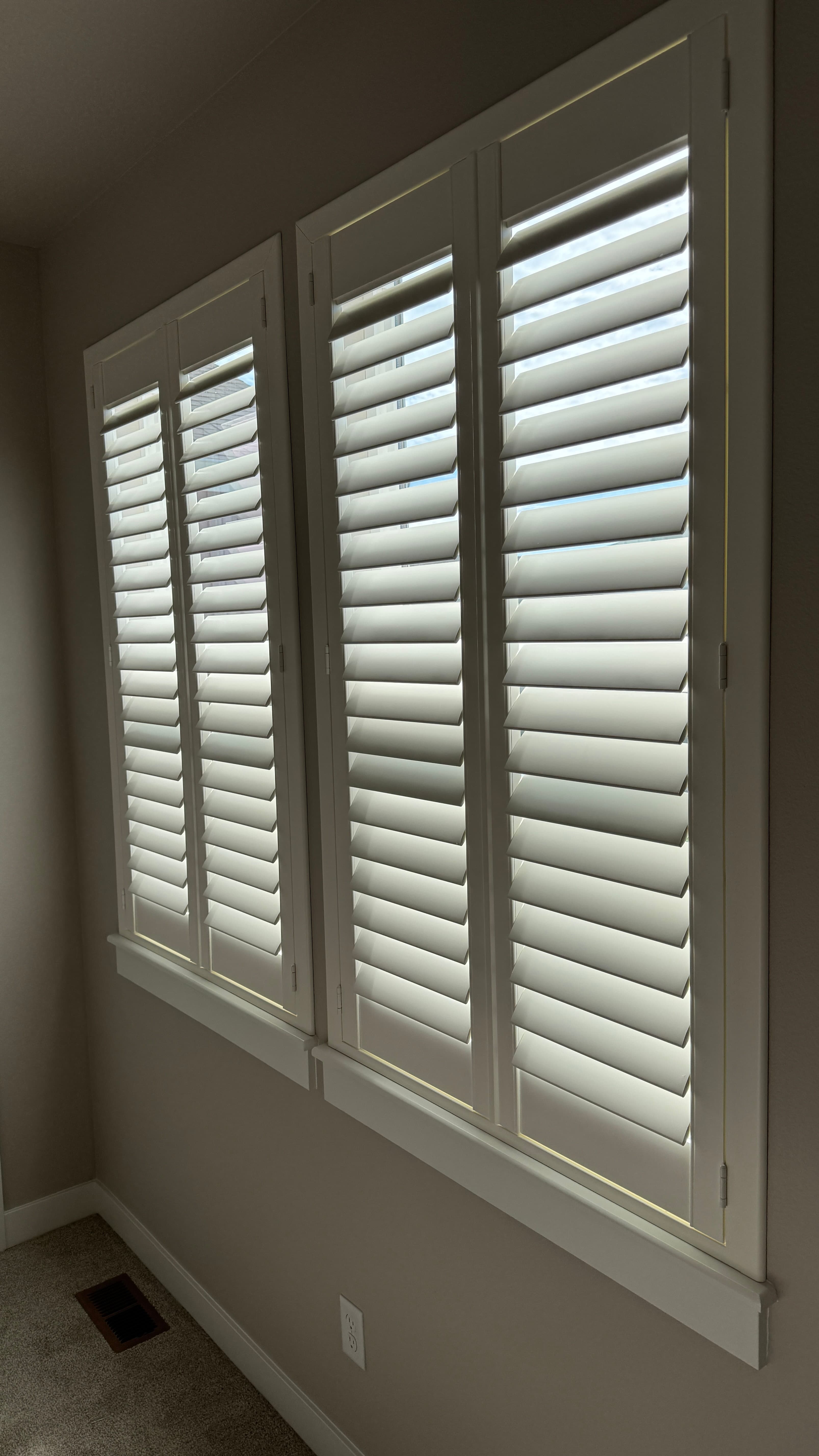Norman plantation shutters with split-tilt design installed by Luxe Window Works in a new construction home in North Idaho, shown with louvers angled open to admit natural light while maintaining privacy.