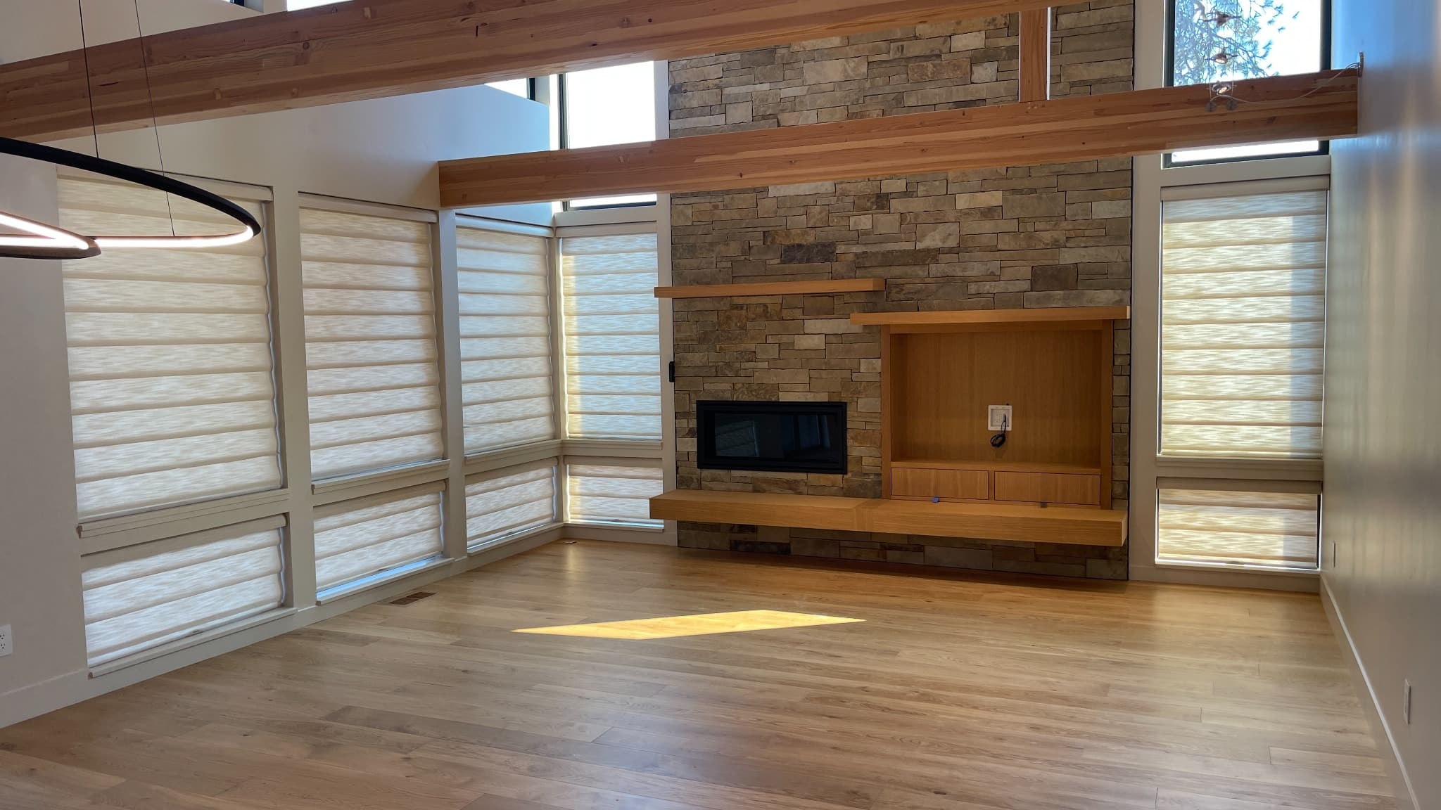 Luxe Window Works installation of cream shades beside a stone fireplace, before the home was furnished