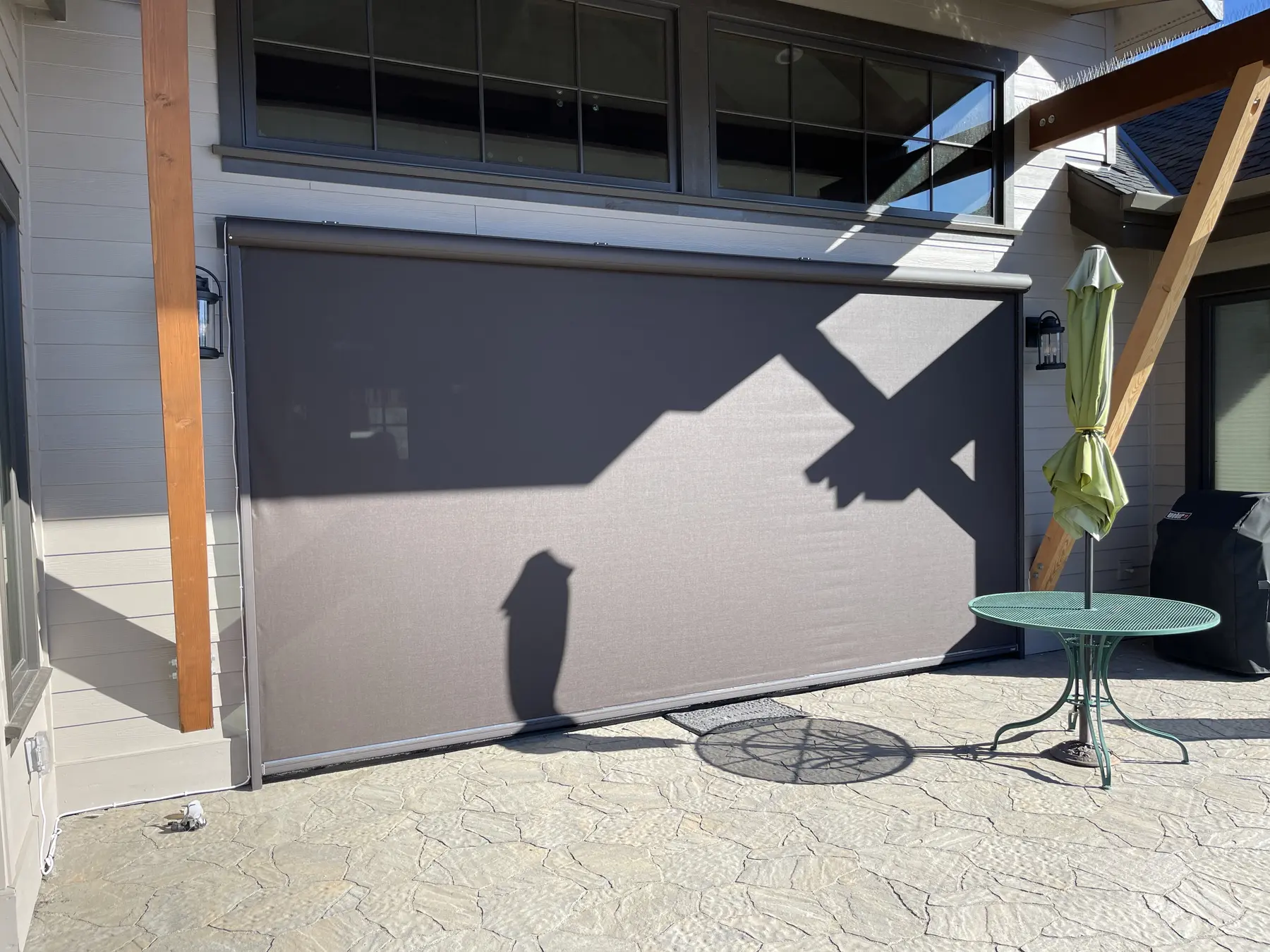 Large exterior solar screen lowered over a patio opening