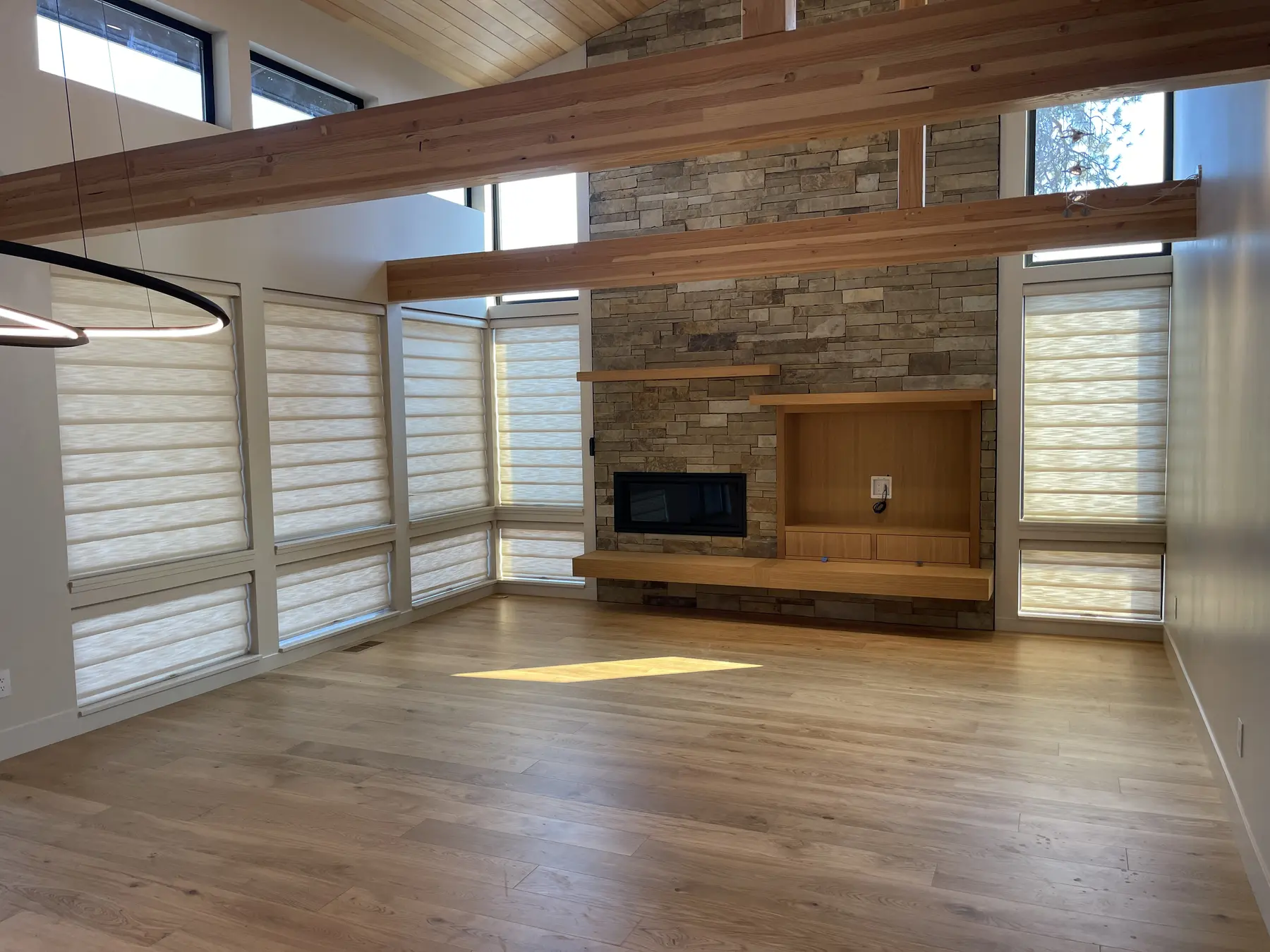 Flat panel Roman shades installed around a stone fireplace in a vaulted great room