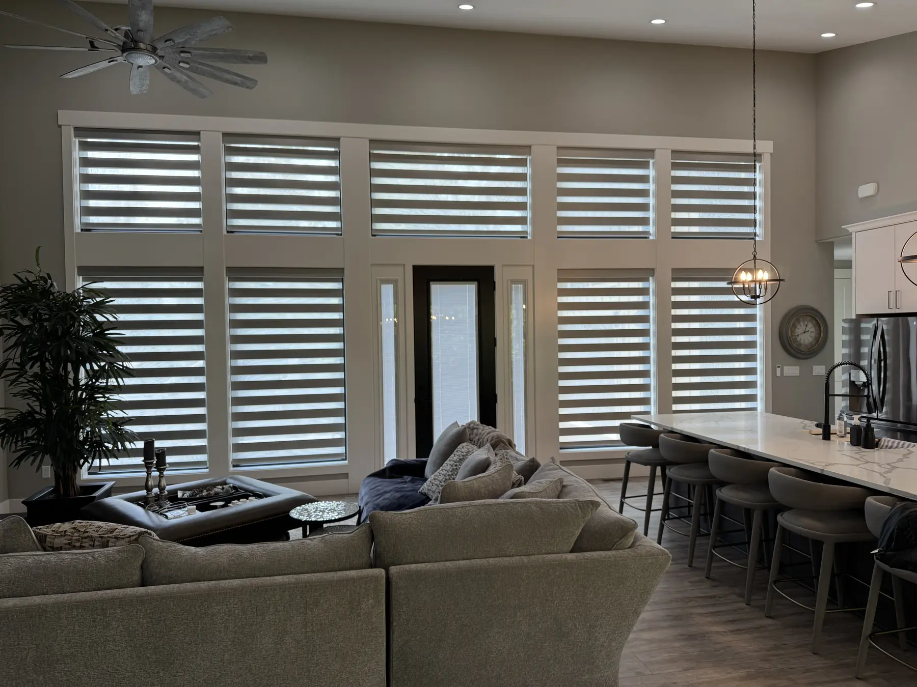 Coordinated layered shades across a large open living room and kitchen