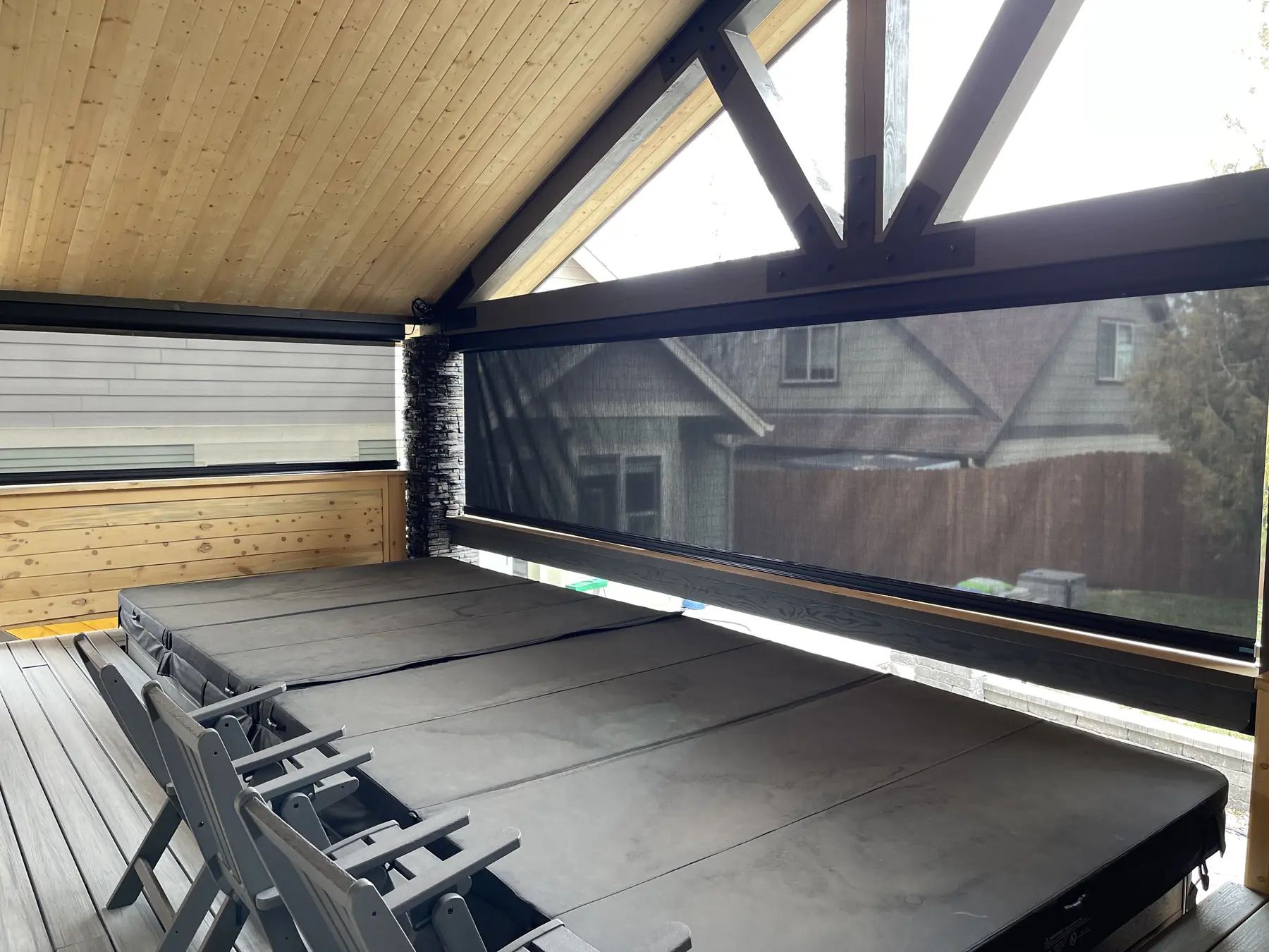Motorized outdoor solar screen enclosing a covered hot tub patio