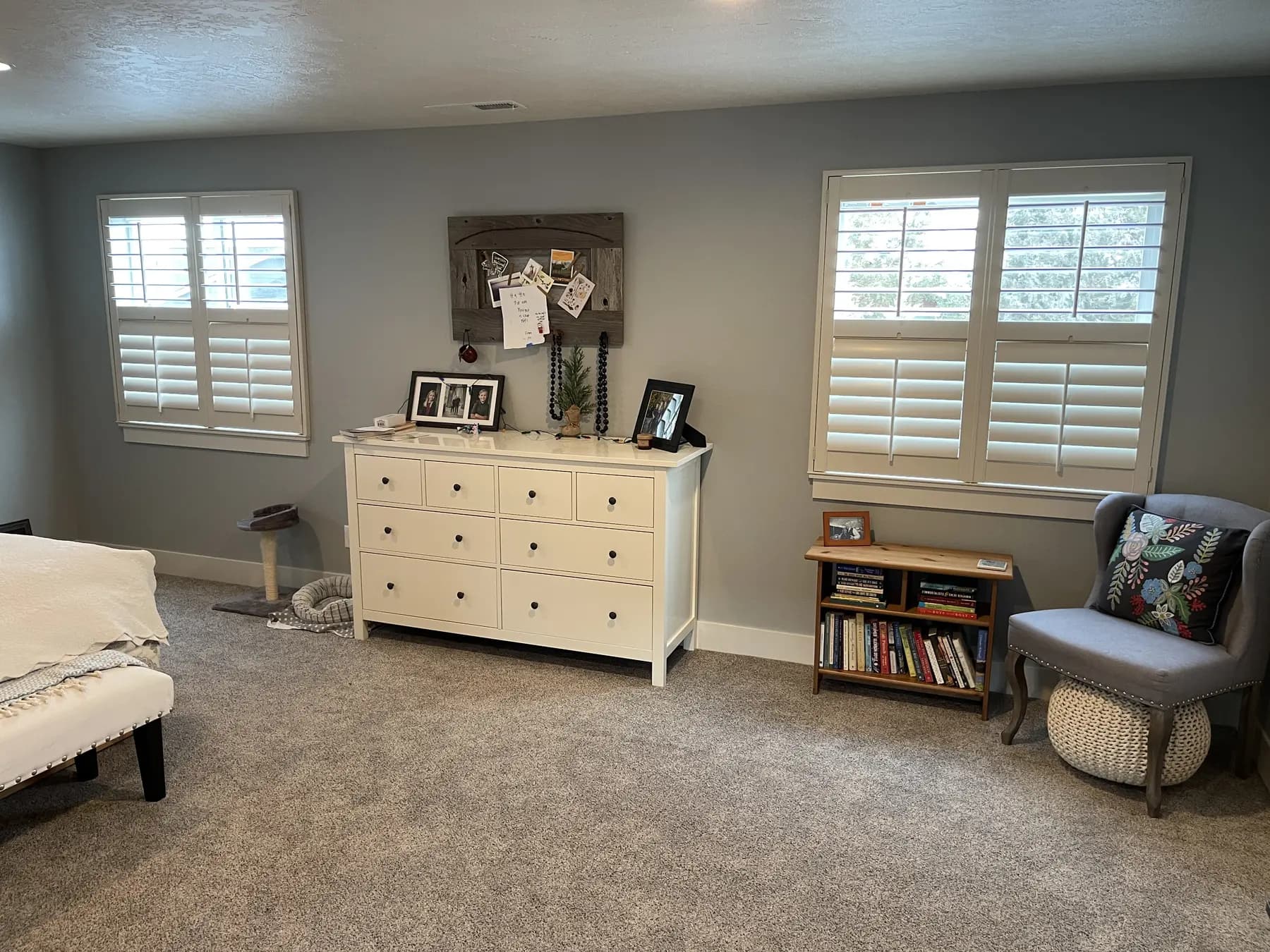 White shutters fitted to two windows in a furnished bedroom