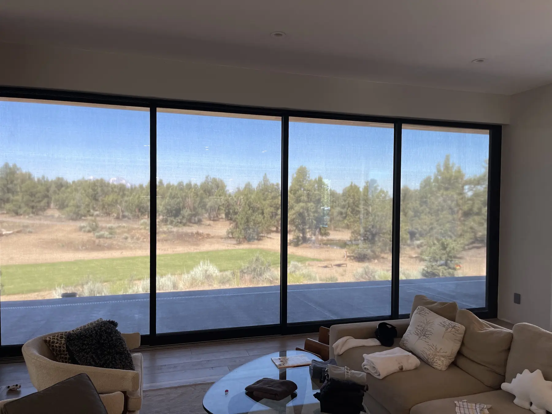 Large solar screen reducing glare across a scenic living-room window