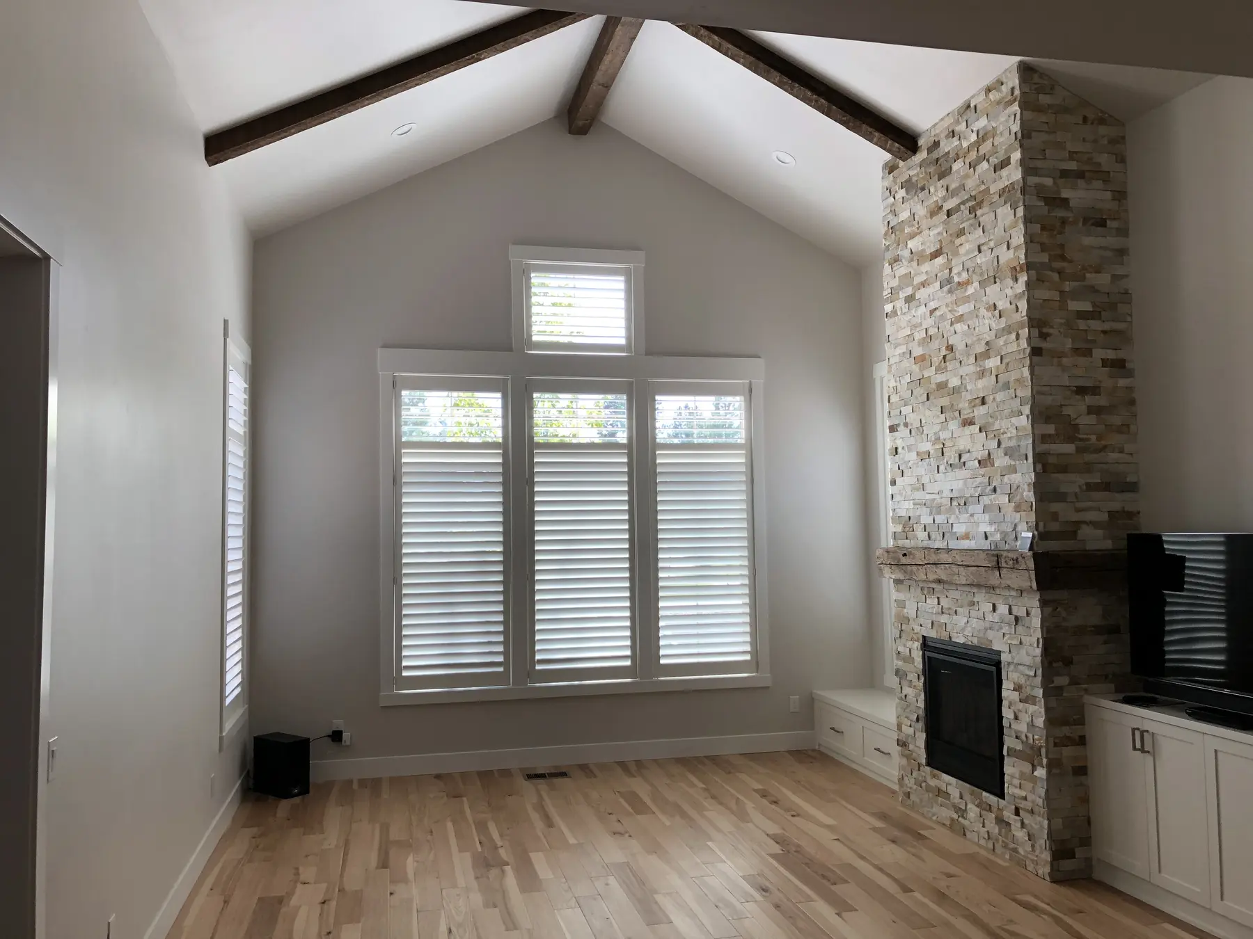 White shutters installed beneath transom windows in a vaulted room