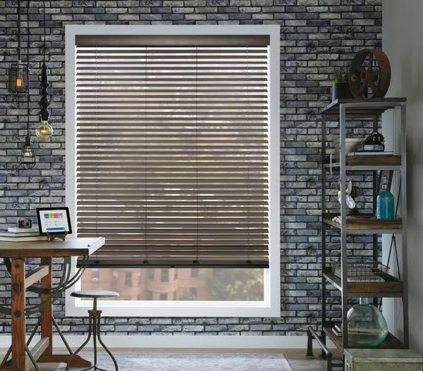 Close-up of wood grain blind slats in front of an exposed brick wall, showing the texture and warmth of composite wood blind material