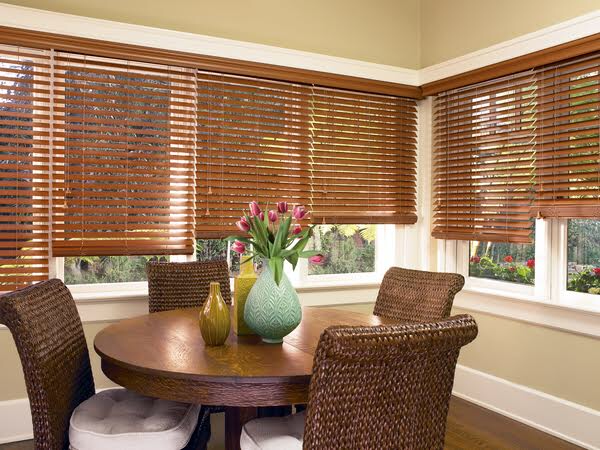 Wood blinds in a warm dining room showing the rich natural tones and privacy control that faux wood and composite blinds can replicate